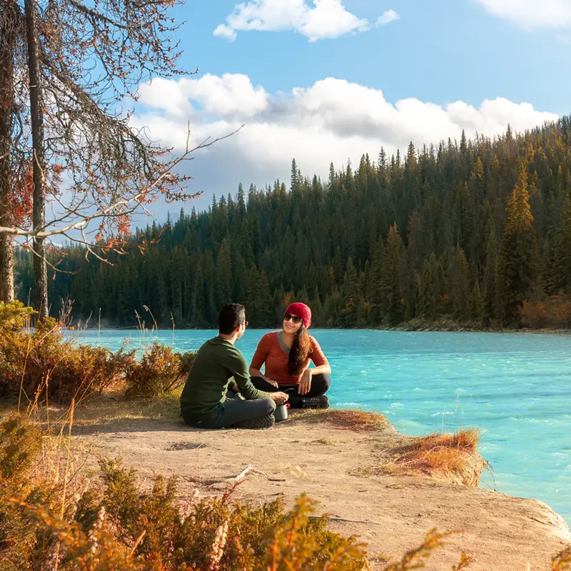 Couple sitting next to Turquoise colored river in Banff National Park