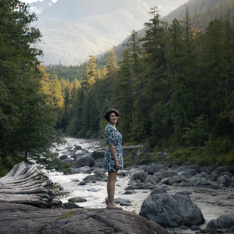 Girl standing next to a river in the Vancouver Island wilderness